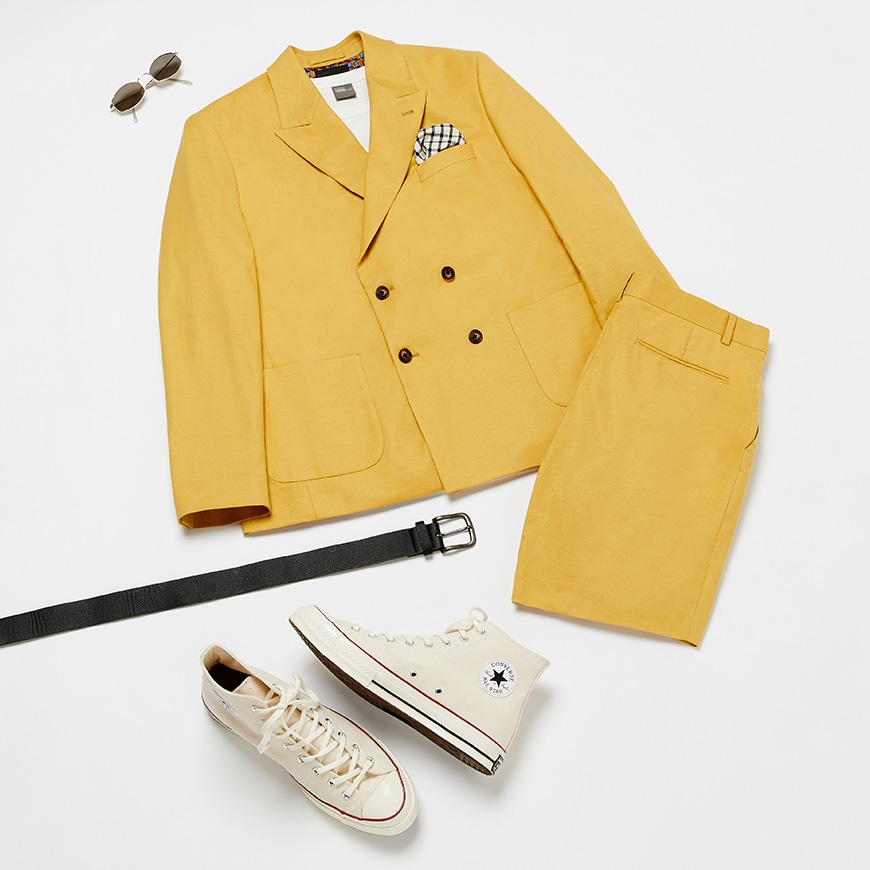 A flat lay of a yellow suit complete with converse, T-shirt and sunglasses. Available at ASOS.