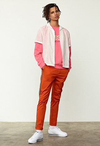 Model wearing a pink Stussy sweatshirt and orange trousers | ASOS Style Feed