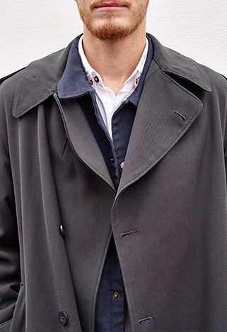 Close up of John Agnew in grey trench coat
