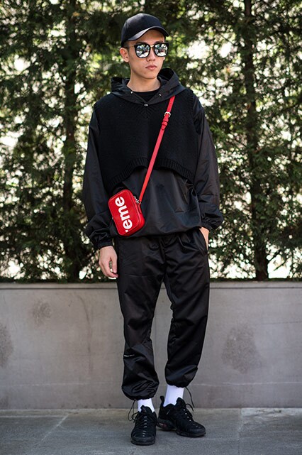 MFW SS18 Street Style featuring a street styler in a black tracksuit, Nike Air Max TN trainers and a Louis Vuitton x Supreme flight bag | ASOS Style Feed