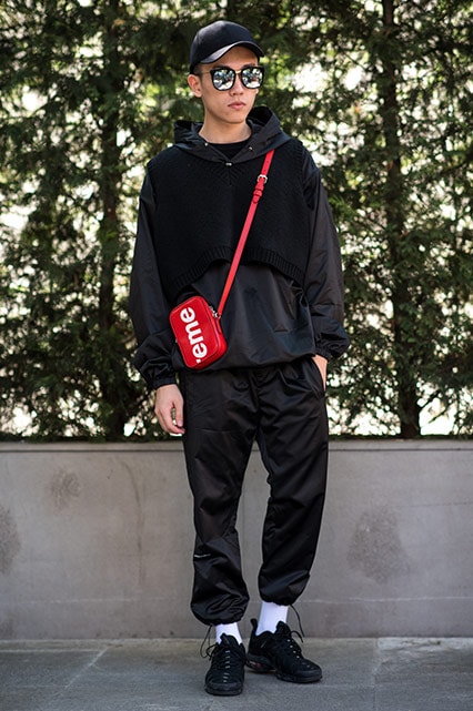 MFW SS18 Street Style featuring a street styler in a black tracksuit, Nike Air Max TN trainers and a Louis Vuitton x Supreme flight bag | ASOS Style Feed
