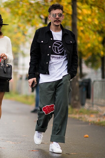 PFW SS18 Street Style featuring a street styler in a Gosha Rubchinskiy T-shirt, boxy black jacket, khaki wide-leg trousers and white trainers | ASOS Style Feed