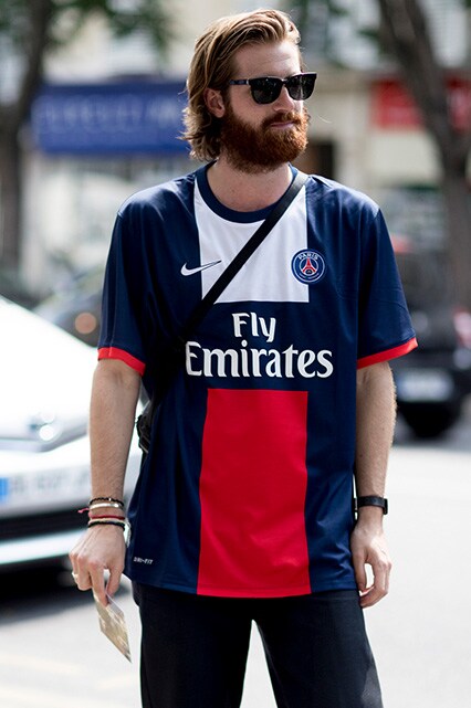 A street-styler wearing a football shirt, black jeans, a black bum bag and Wayfarer sunglasses | ASOS Style Feed