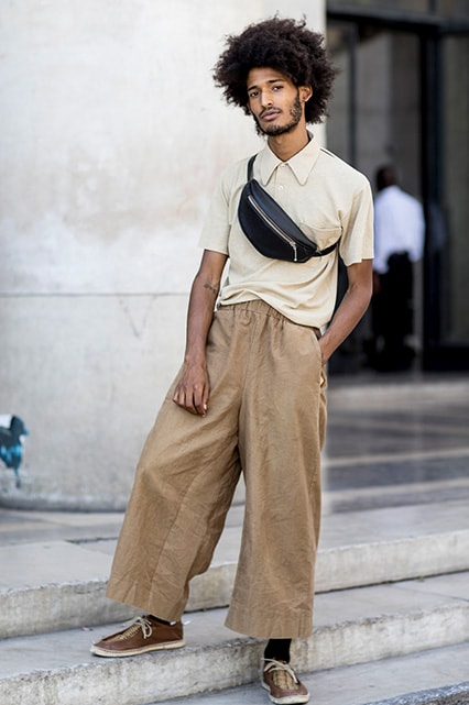 A street-styler wearing a beige polo neck, brown wide-leg trousers, brown woven shoes and a black leather bum bag | ASOS Style Feed
