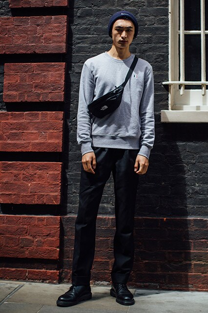 A street-styler wearing an Ami sweatshirt, a Supreme beanie hat, black trousers, black lace-up boots and a The North Face bum bag | ASOS Style Feed