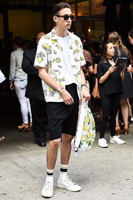 A street-styler wearing a white T-shirt, printed shirt and long shorts | ASOS Style Feed