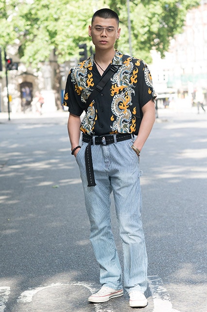 A street-styler wearing a printed revere collar shirt, trousers and Converse trainers | ASOS Style Feed