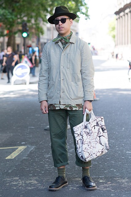 A street-styler wearing a beige coach jacket, scarf, shades, trilby, khaki trousers and lace-up shoes | ASOS Style Feed 