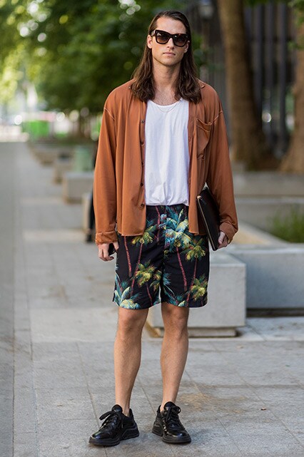 A street-styler wearing a white vest, oversized shirt, printed shorts and trainers | ASOS Style Feed