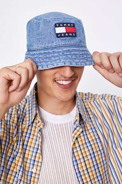 A model wearing a Tommy Hilfiger hat, white T-shirt, check short-sleeved shirt, denim shorts and New Balance trainers available at ASOS | ASOS Style Feed