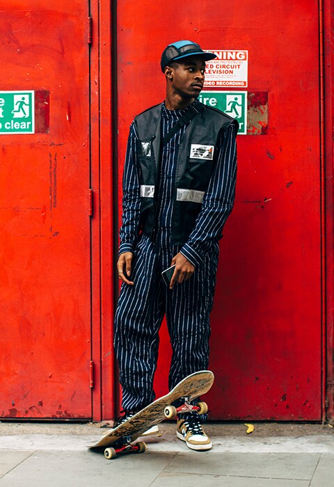 A street-styler at LFWM's SS19 wearing a cap, striped co-ord and gilet | ASOS Style Feed