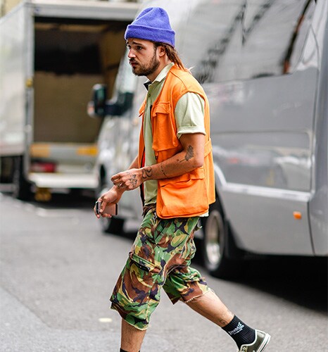 A street-styler wearing a gilet, a beanie, a top and camouflage shorts | ASOS Style Feed