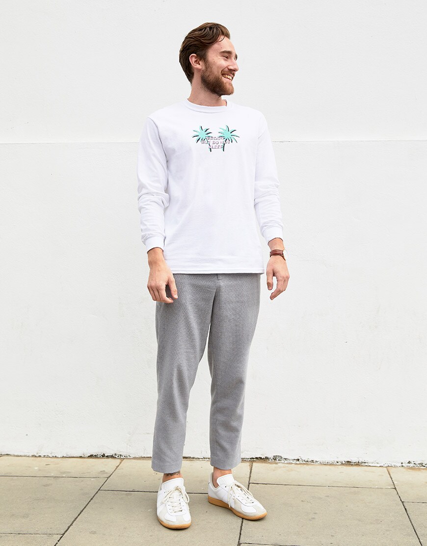 Ashley wearing  a Crooked Tongues long-sleeved tee, grey trousers and white trainers | ASOS Style Feed