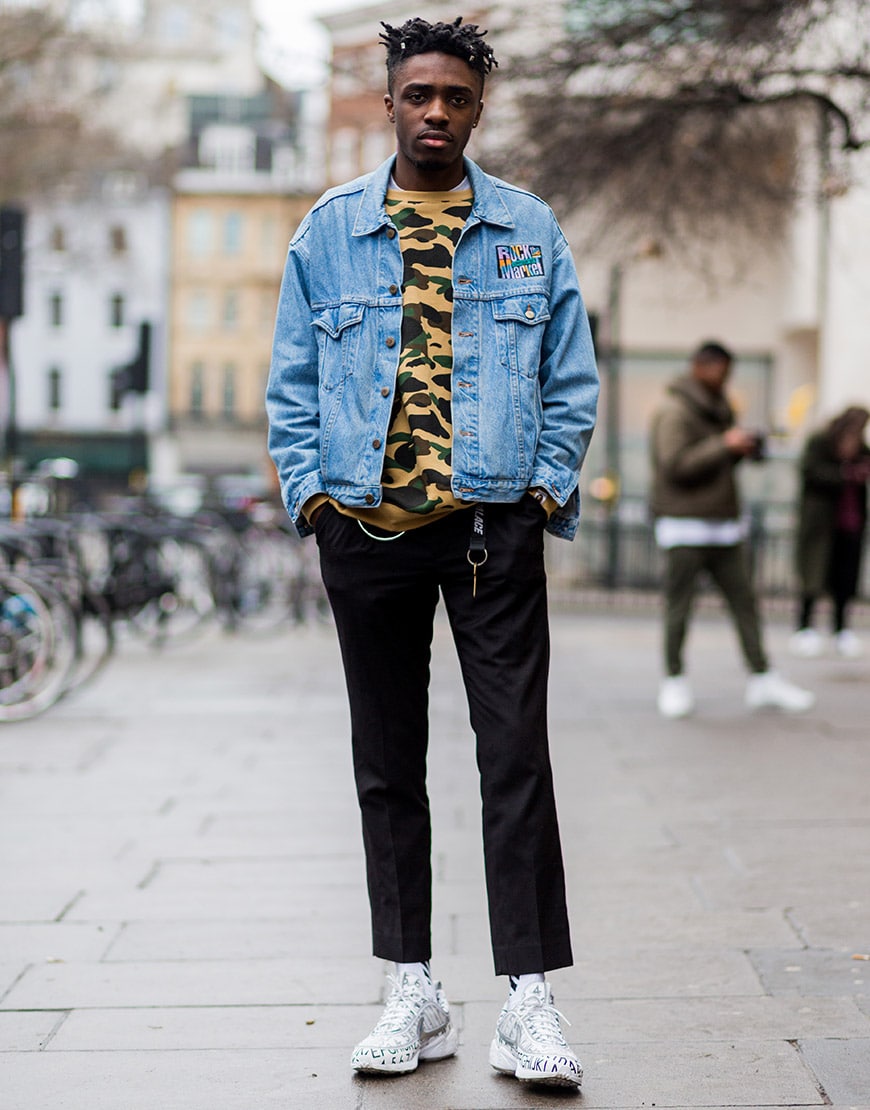 A street-styler wearing a denim jacket, camo-print jumper, trousers and Nike Spiridon trainers | ASOS Style Feed