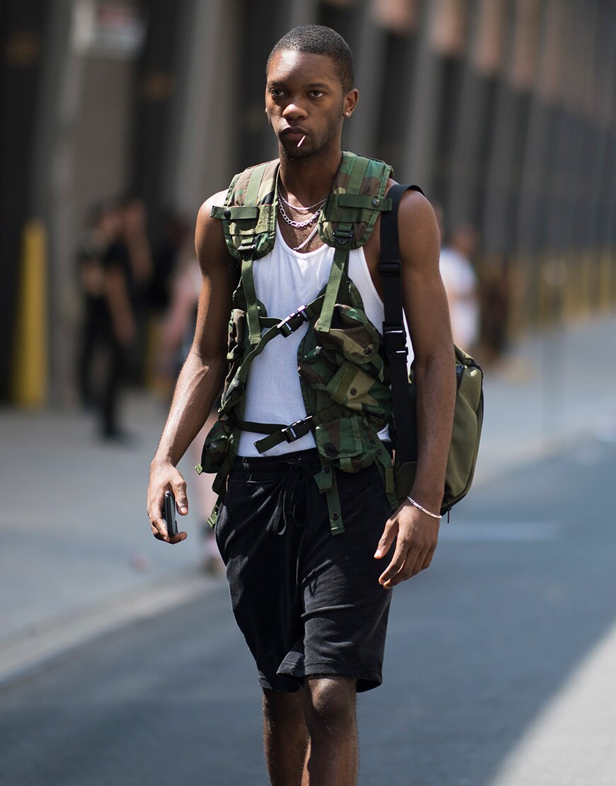 A street-styler wearing a white vest, shorts, chains and a camo-print vest | ASOS Style Feed