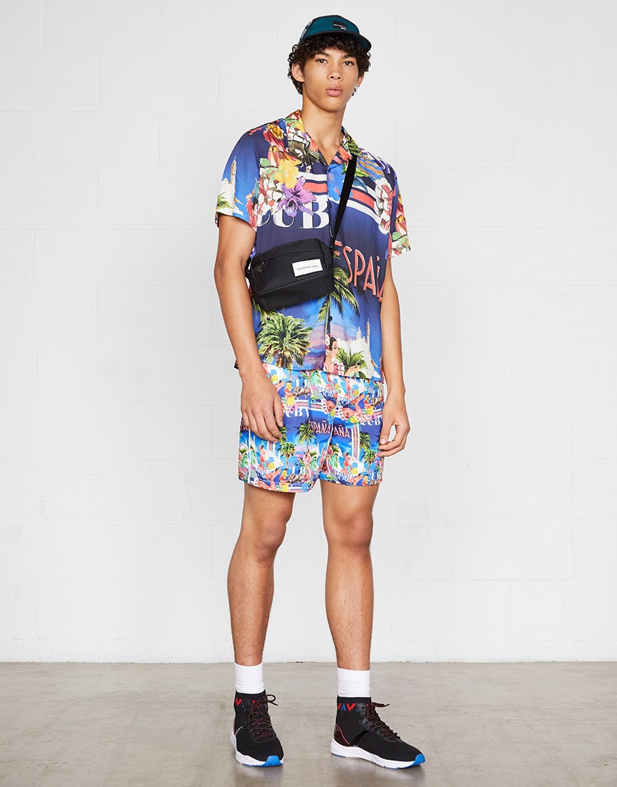 A model wearing a tropical-print shirt and matching shorts with a cap, cross-body bag and hi-top trainers | ASOS Style Feed