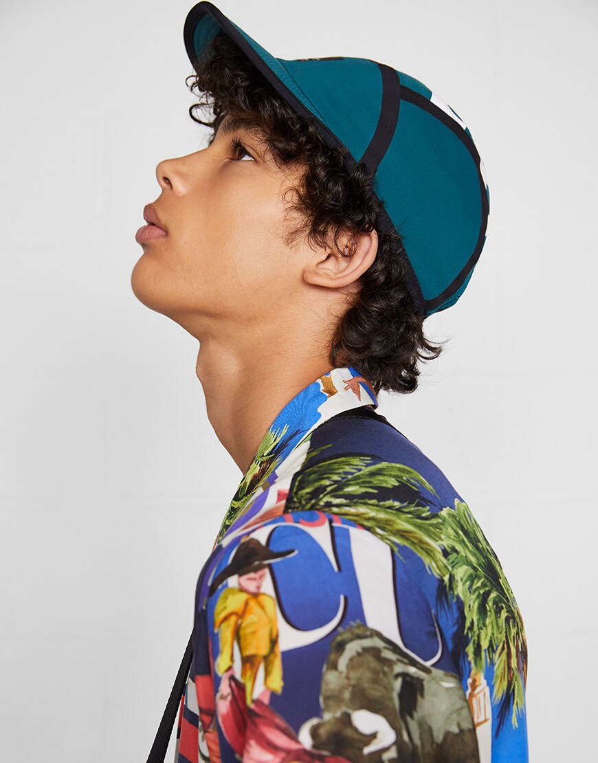 A model wearing a cap and a tropical-print shirt | ASOS Style Feed