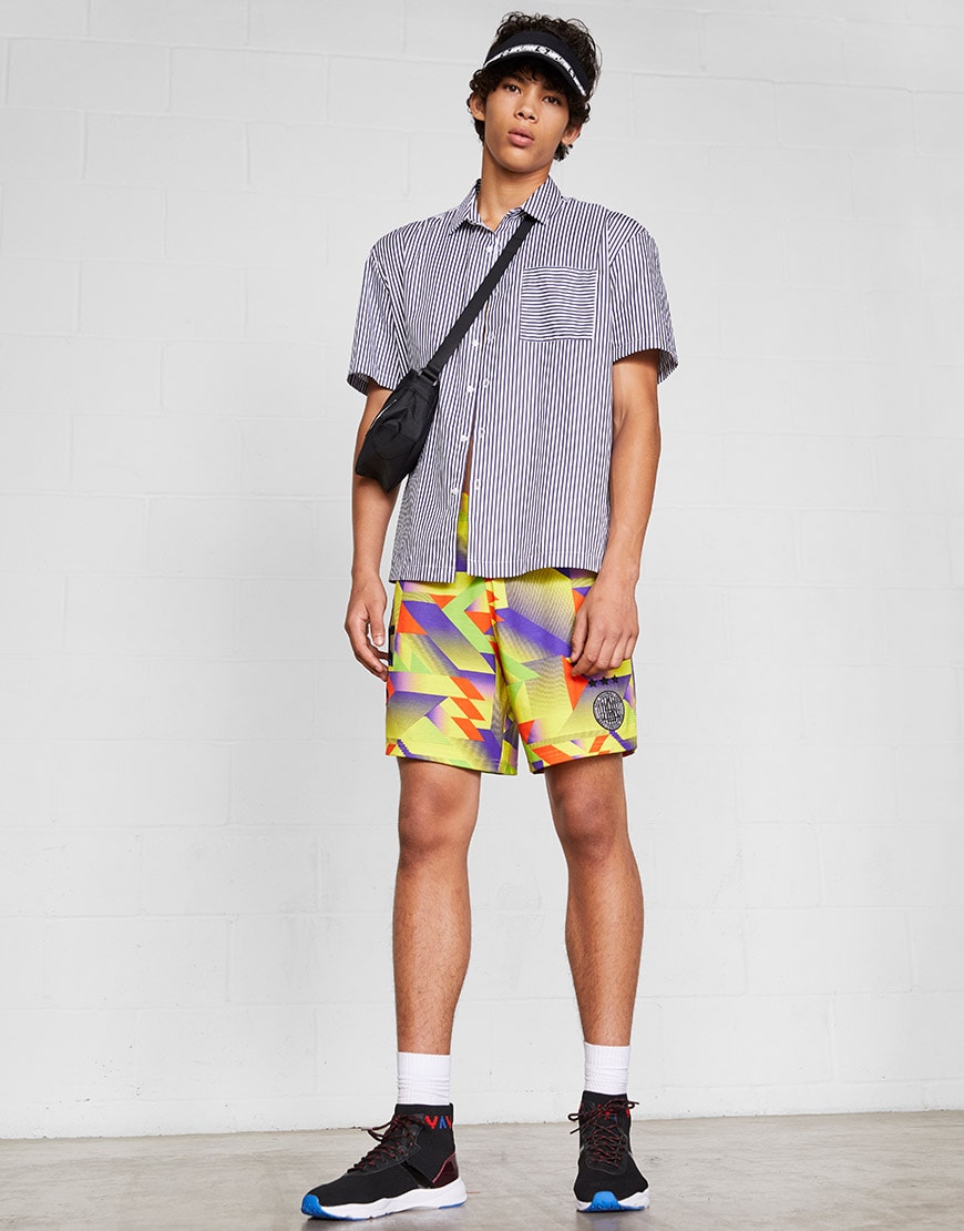 A model wearing ASOS 4505 shorts, a striped shirt, visor, cross-body bag and hi-top trainers | ASOS Style Feed
