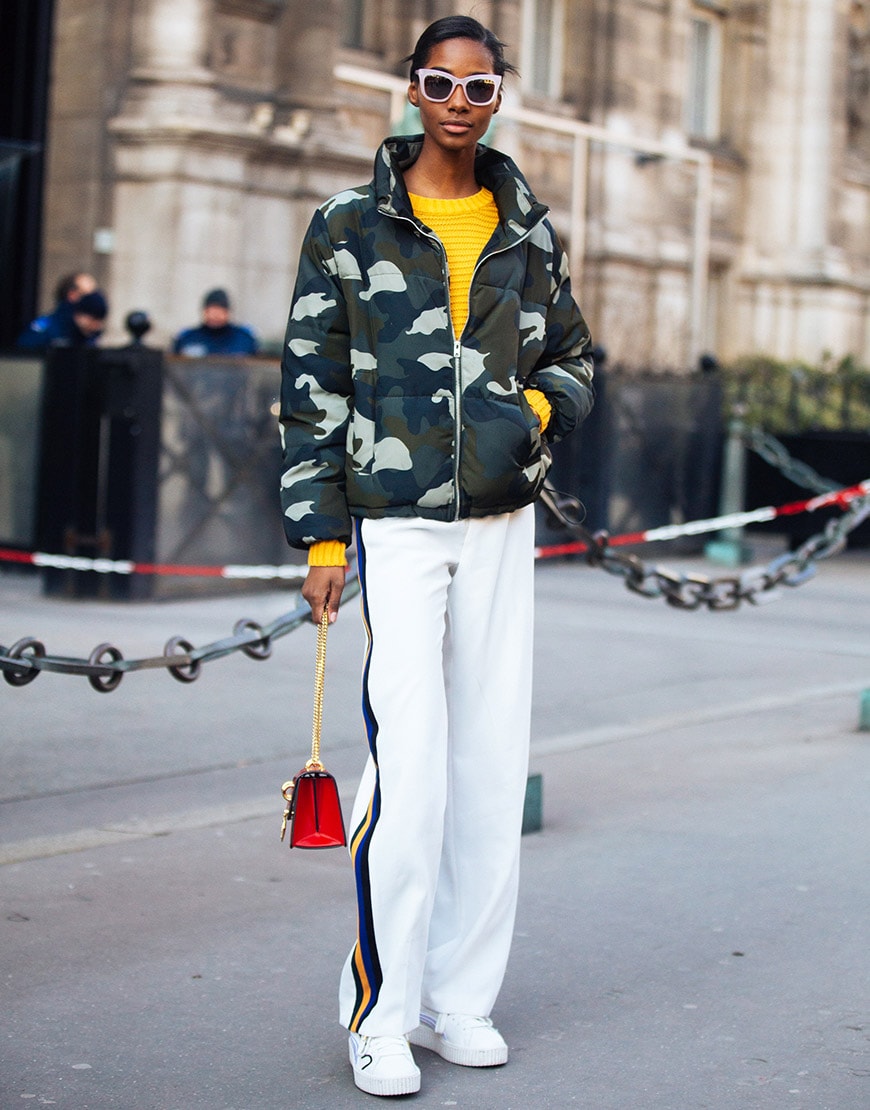 A model wearing shades, a yellow jumper, a camo puffer jacket and side-stripe tracksuit bottoms | ASOS Style Feed