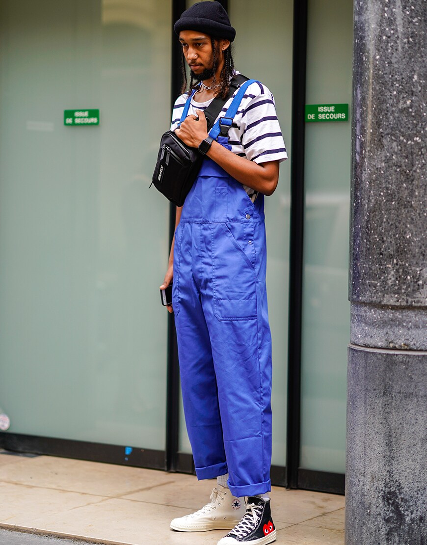 A street-styler wearing a Breton-stripe T-shirt, dungarees, Comme des Garçon Converse trainers, a beanie hat and a cross-body bag | ASOS Style Feed