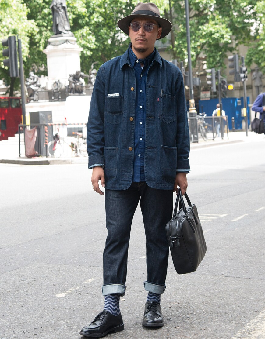 A street-styler wearing a French worker jacket, jeans, a denim shirt, a fedora, clear-framed sunglasses and Oxford shoes | ASOS Style Feed