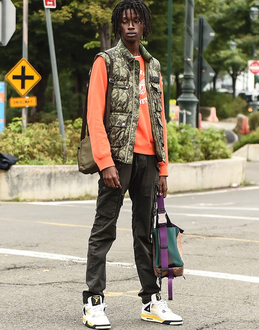 A street-styler wearing an orange top, gilet, cargo trousers and Nike Air Jordan trainers | ASOS Style Feed