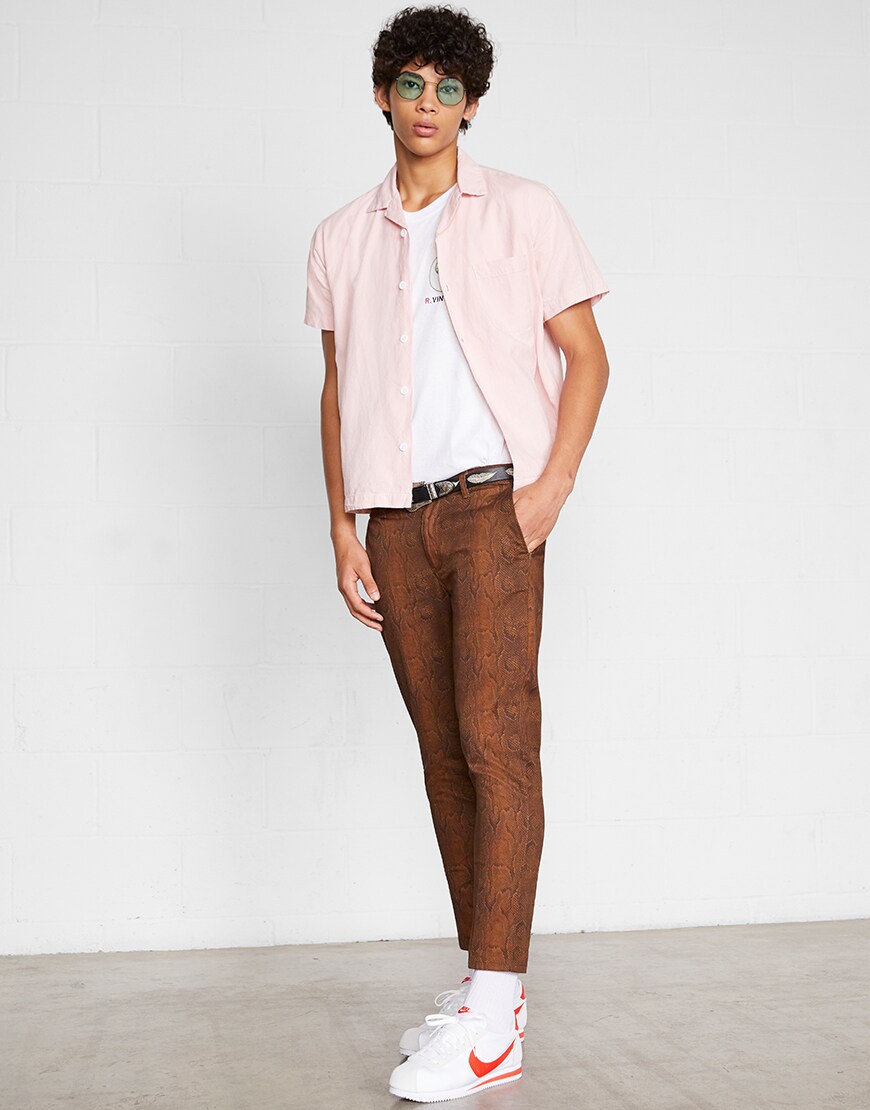A model wearing a graphic-print T-shirt, pink shirt, snakeskin trousers, shades and Nike Cortez trainers | ASOS Style Feed