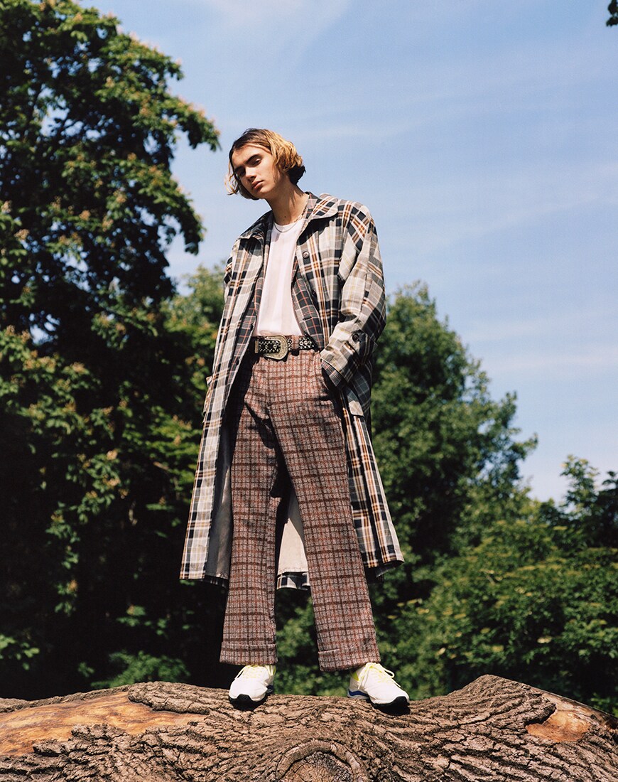 Editorial Bild eines jungen Mannes mit einem karierten Mantel und Hose