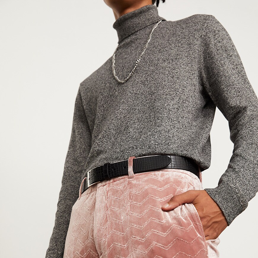 A model wearing a grey polo-neck top with pink corduroy trousers and a black belt | ASOS Style Feed