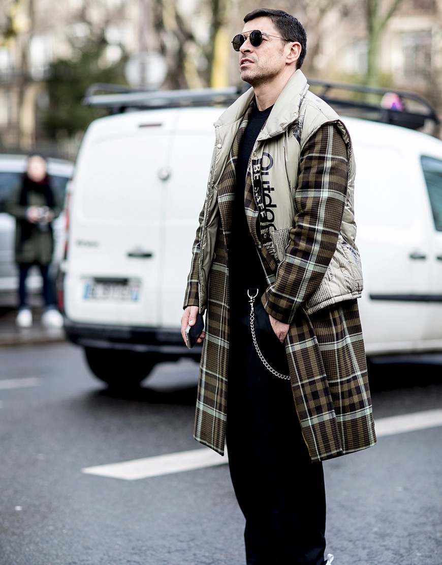A stylish guy wearing a padded gilet over a check coat