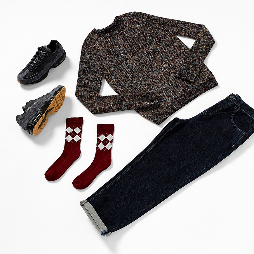 A flat shot of a Christmas Day outfit available on ASOS. It includes a jumper with metallic details, dark-wash jeans, burgundy socks and Nike trainers