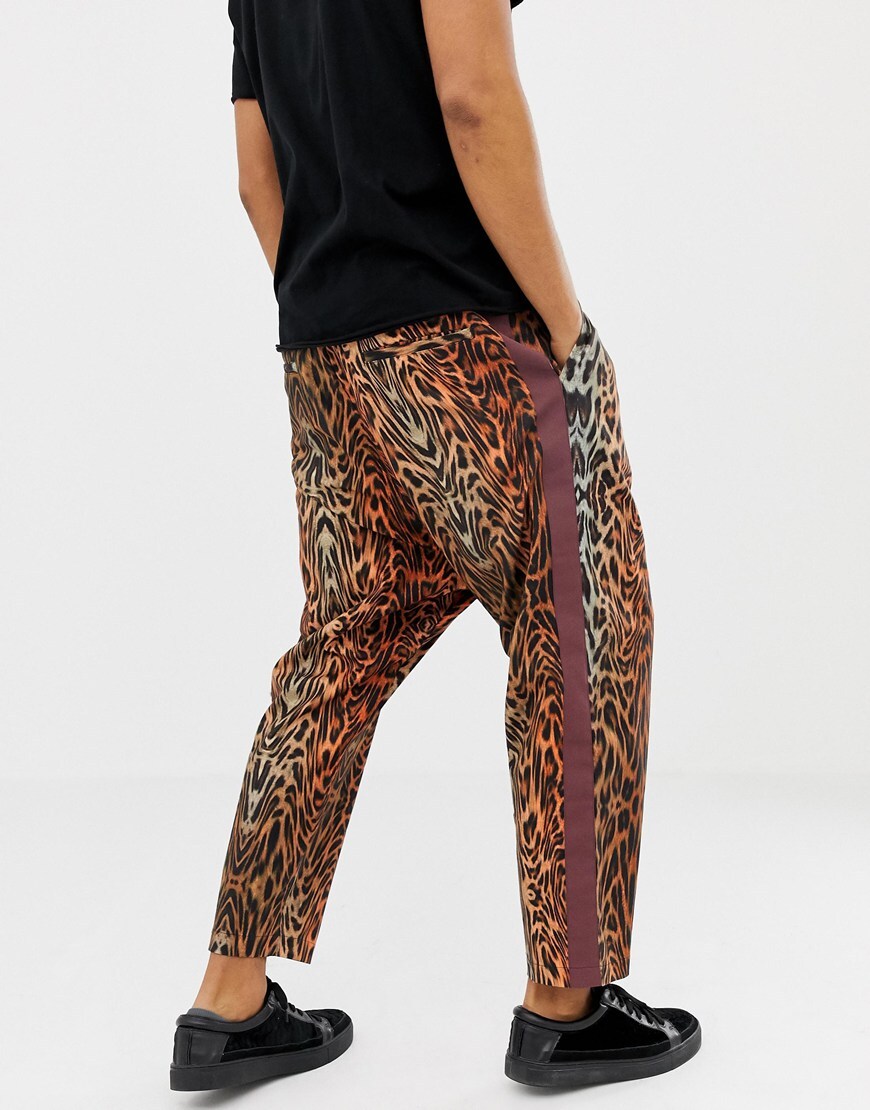 A model wearing leopard print tapered trousers with red side stripes 