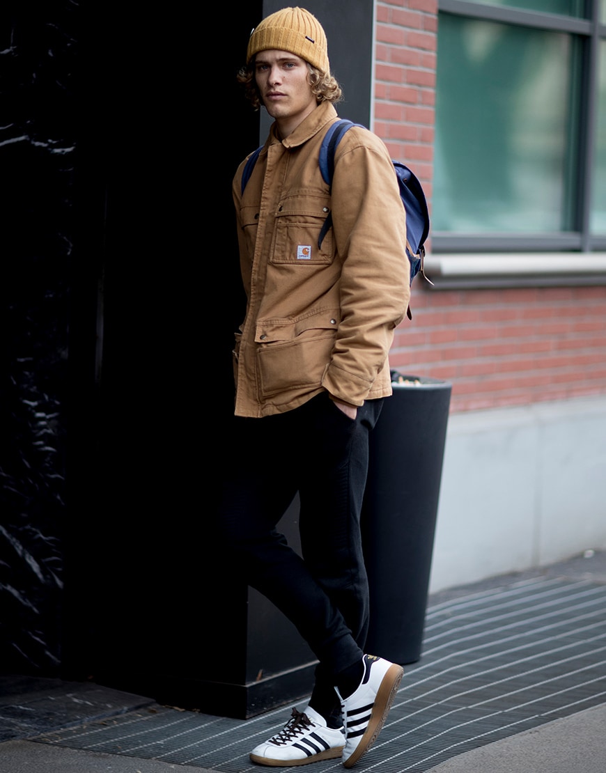 A street-styler wearing a Carhartt jacket, a yellow beanie, back pack, jeans and trainers | ASOS Style Feed