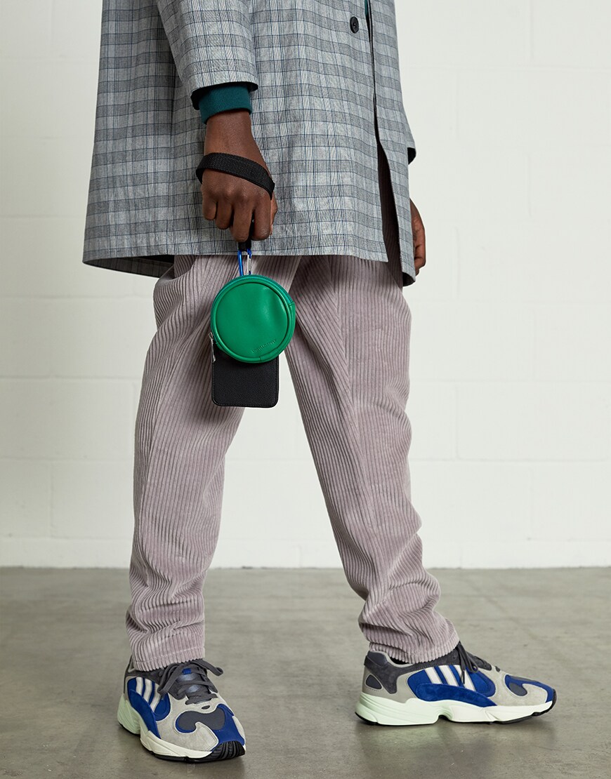 A picture of a model wearing an ASOS White outfit including a checked mac, corduroy trousers and adidas trainers