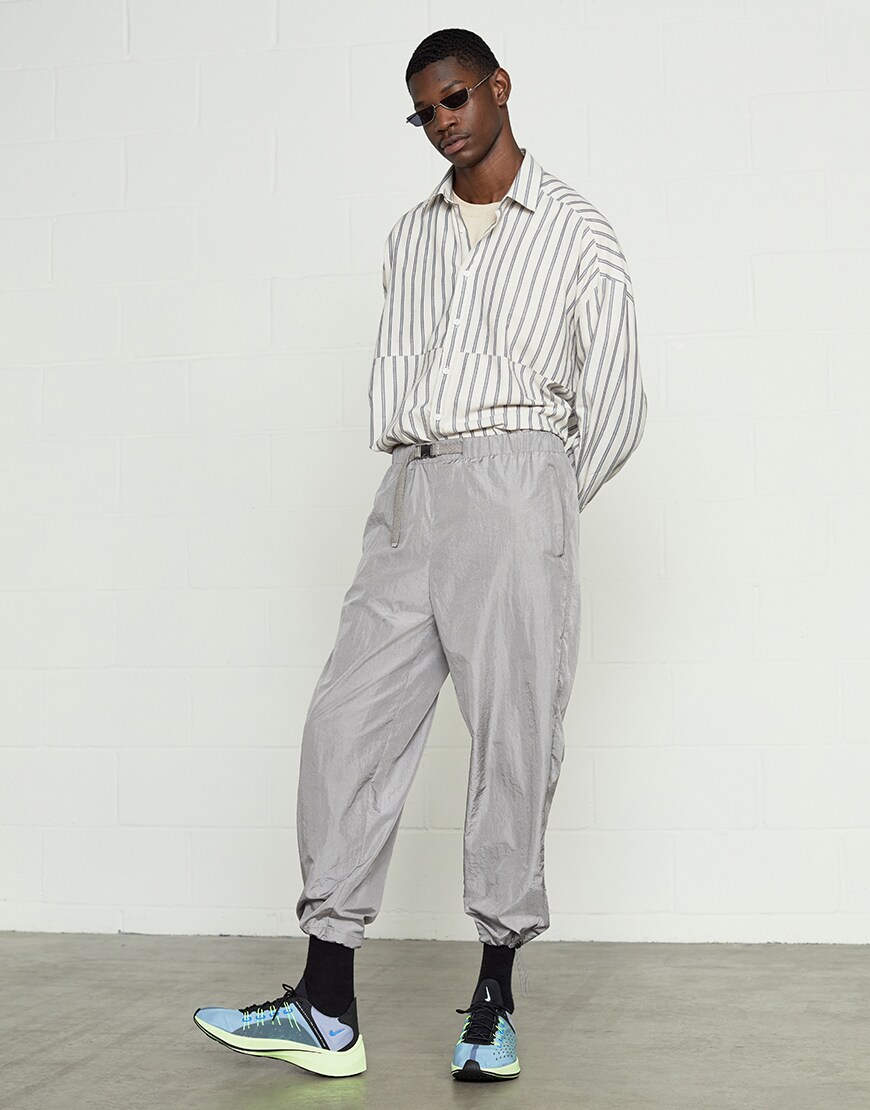 A picture of a model wearing an ASOS White outfit including a striped shirt, technical joggers and Nike trainers. Available at ASOS