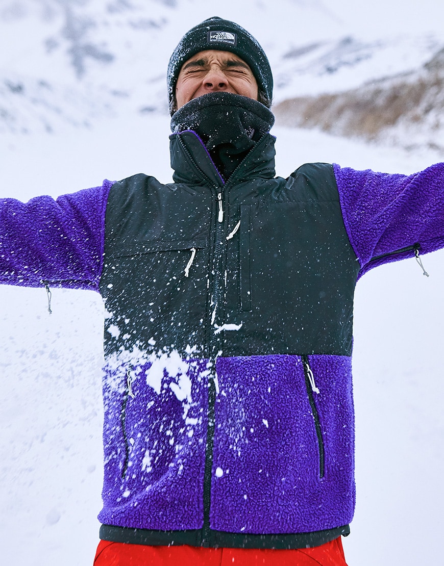 A picture of a man in a snowball fight wearing the Denali fleece and a logo beanie by The North Face. Available at ASOS.