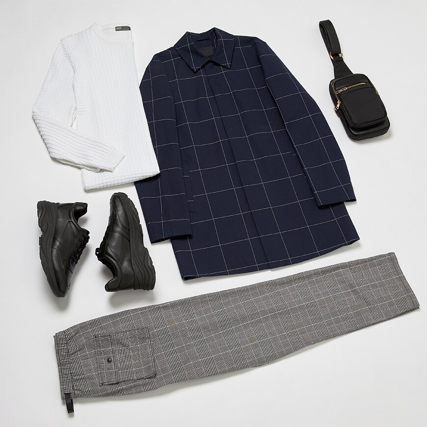 A picture of a back to work flatlay outfit. The look features a check trench coat, a white knitted jumper, chunky black trainers with monochrome check trousers and a cross-body bag. All available on ASOS.