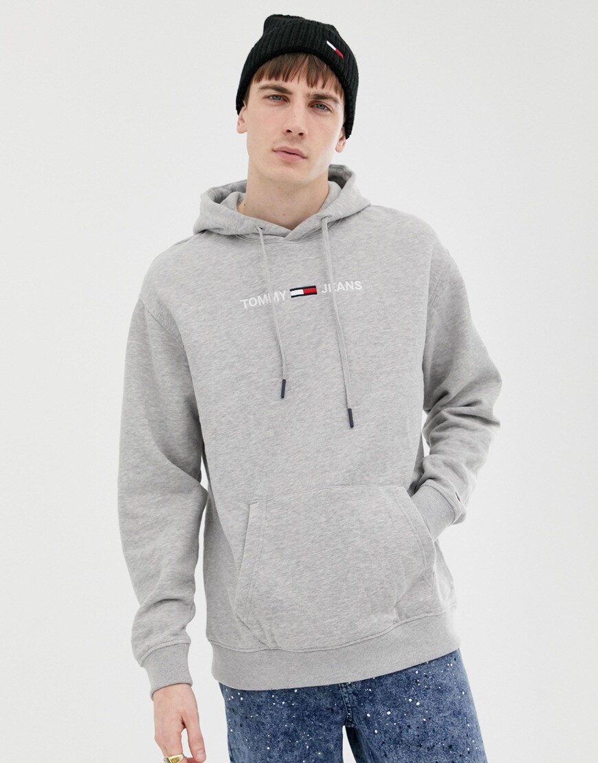 A picture of a man wearing a grey hoodie and black beanie from Tommy Jeans. Available on ASOS.