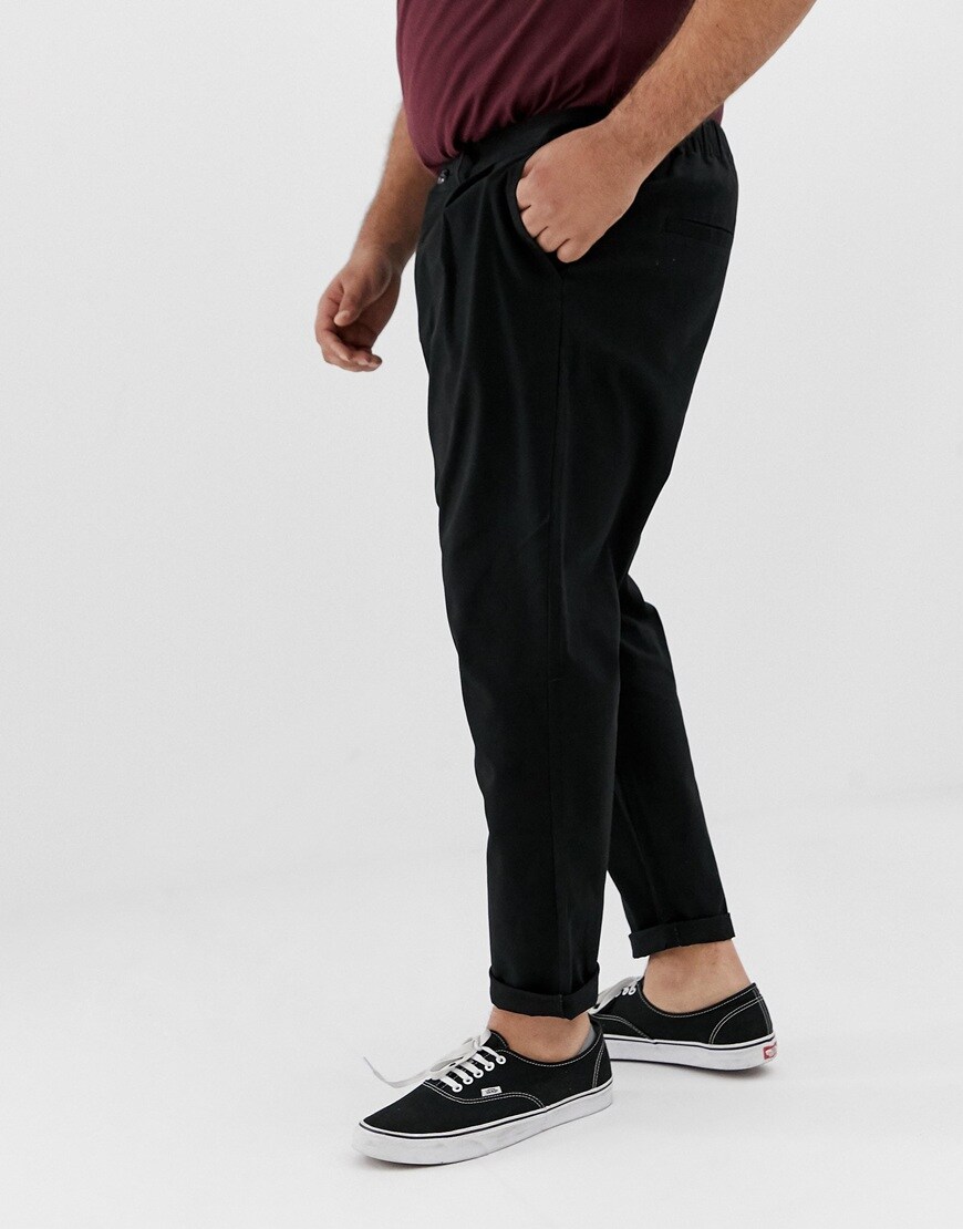 A picture of a man wearing navy plus-size chinos with pleated details. Available at ASOS.