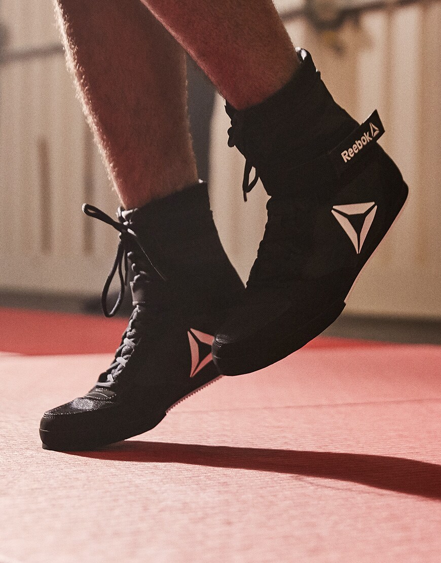 A picture of a man wearing black Reebok boxing boots. Available on ASOS.