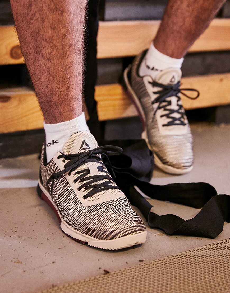 A picture of a man wearing white Reebok gym trainers, available on ASOS.