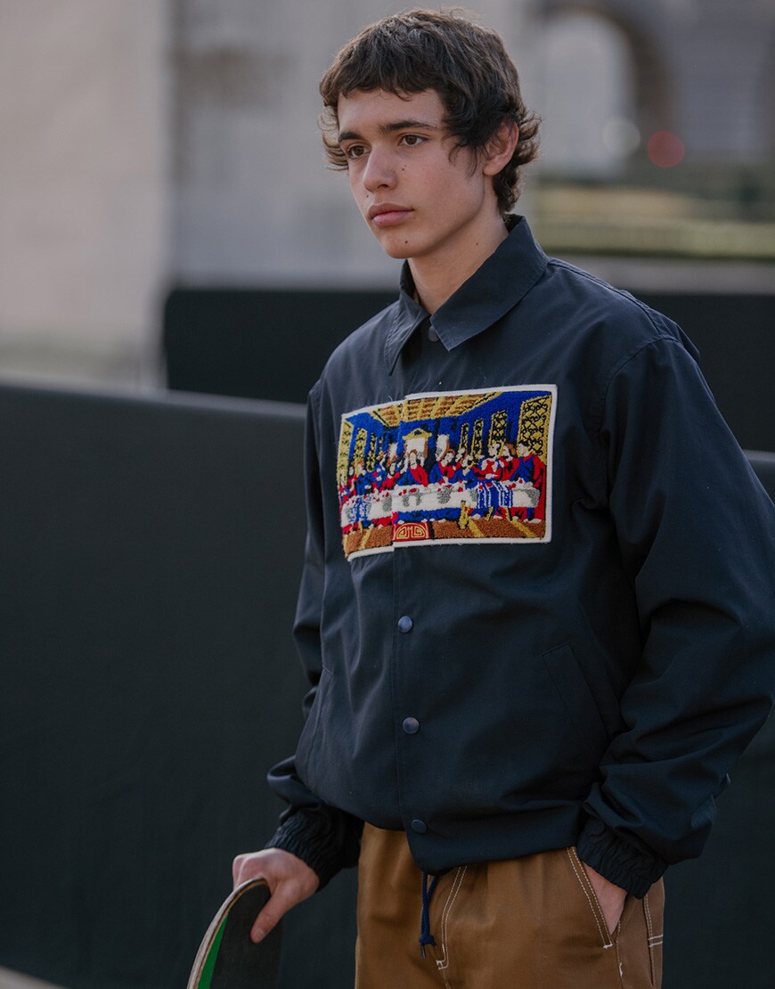 A street-styler at Paris Fashion Week Men's wearing a statement jacket with tan work pants | ASOS Style Feed