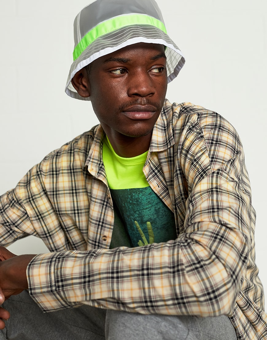 A picture of a man wearing a bucket hat, check shirt and neon T-shirt.