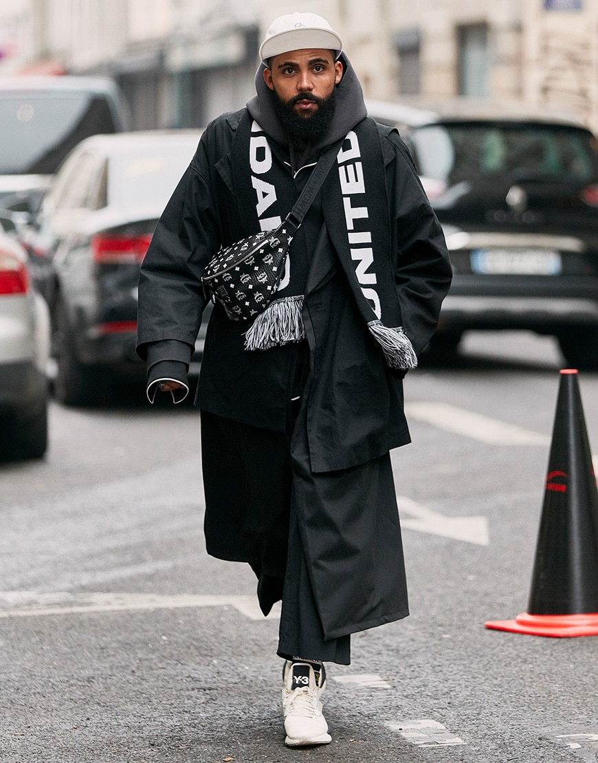 A street-styler wearing an all black 'fit including a cross-body bag and football scarf | ASOS Style Feed