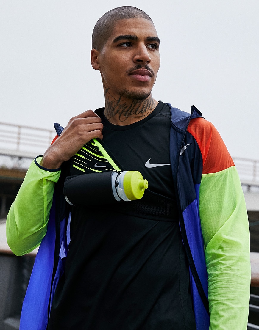 A picture of a man wearing a colour-blocked, lightweight jacket, T-shirt and bum bag from Nike. Available at ASOS.