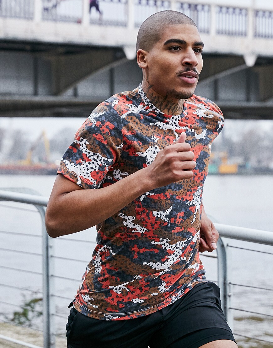A picture of a man running in a Nike running T-shirt featuring an all-over camo print. Available at ASOS.
