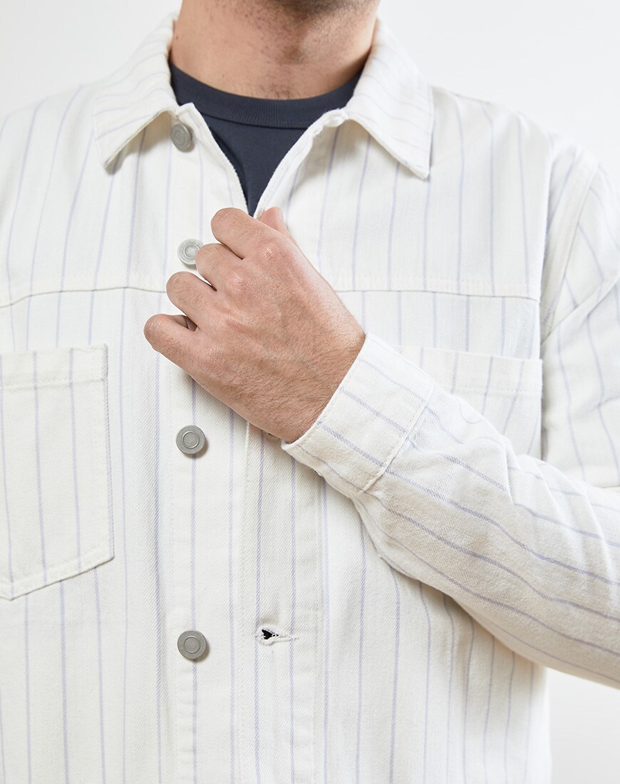 A close up picture of a white denim jacket with pinstripes. Available at ASOS.