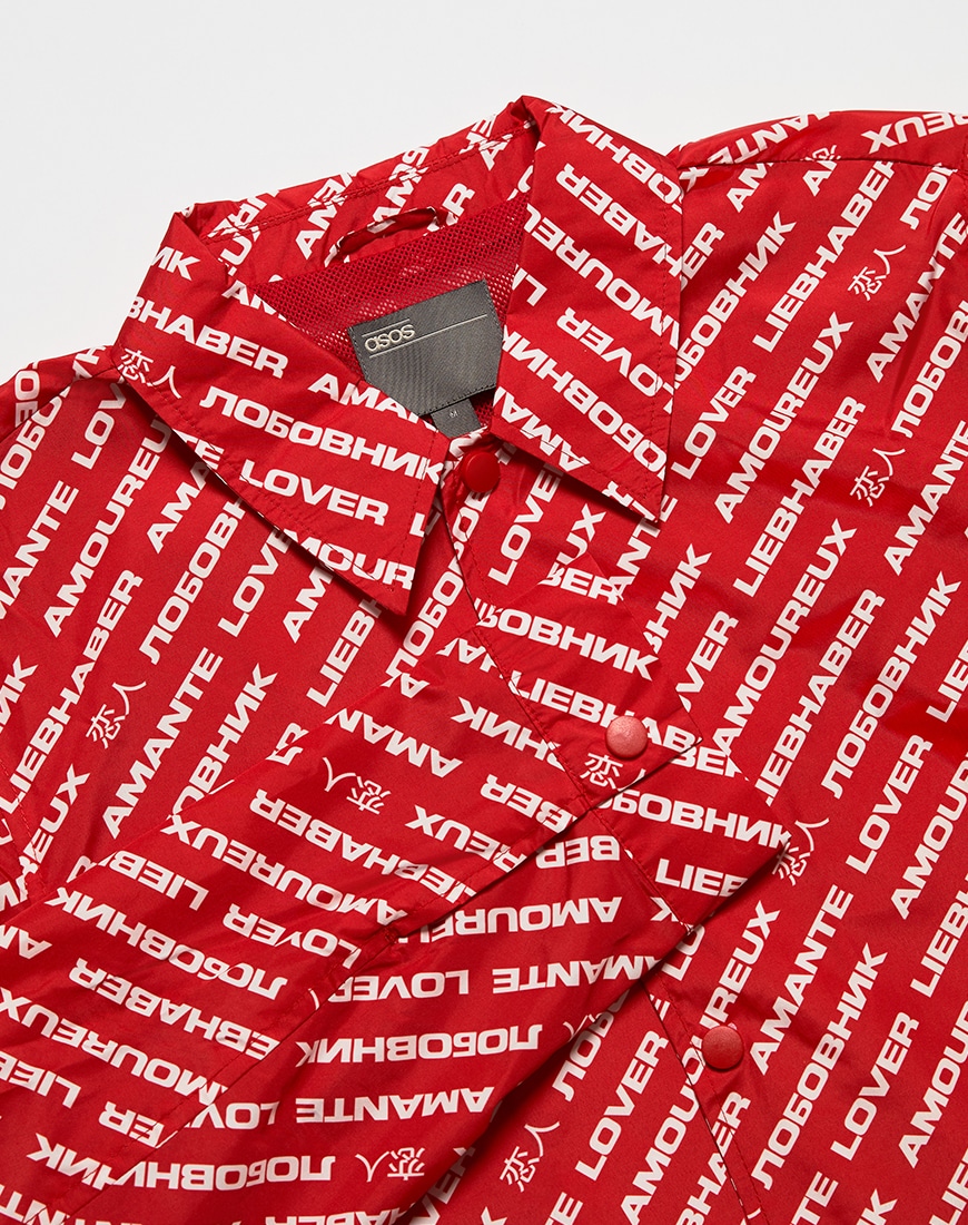 A close up picture of a red and white coach jacket featuring an all-over text print. Available on ASOS.