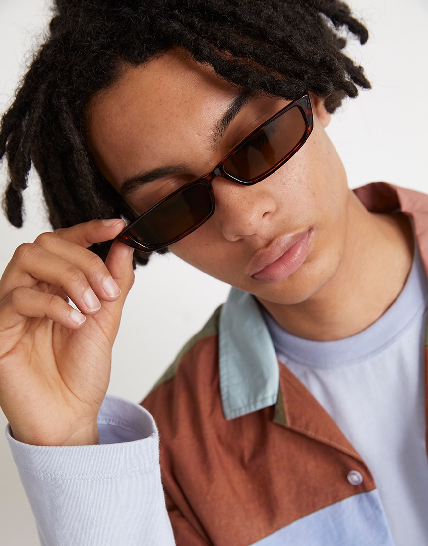 A picture of a model wearing 90s-style sunglasses and an abstract print shirt. Available at ASOS.