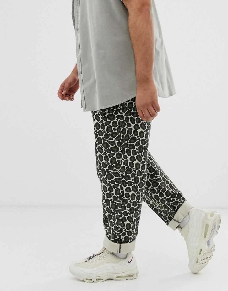 A picture of a model wearing plus-size trousers featuring an all-over leopard print. Available at ASOS.